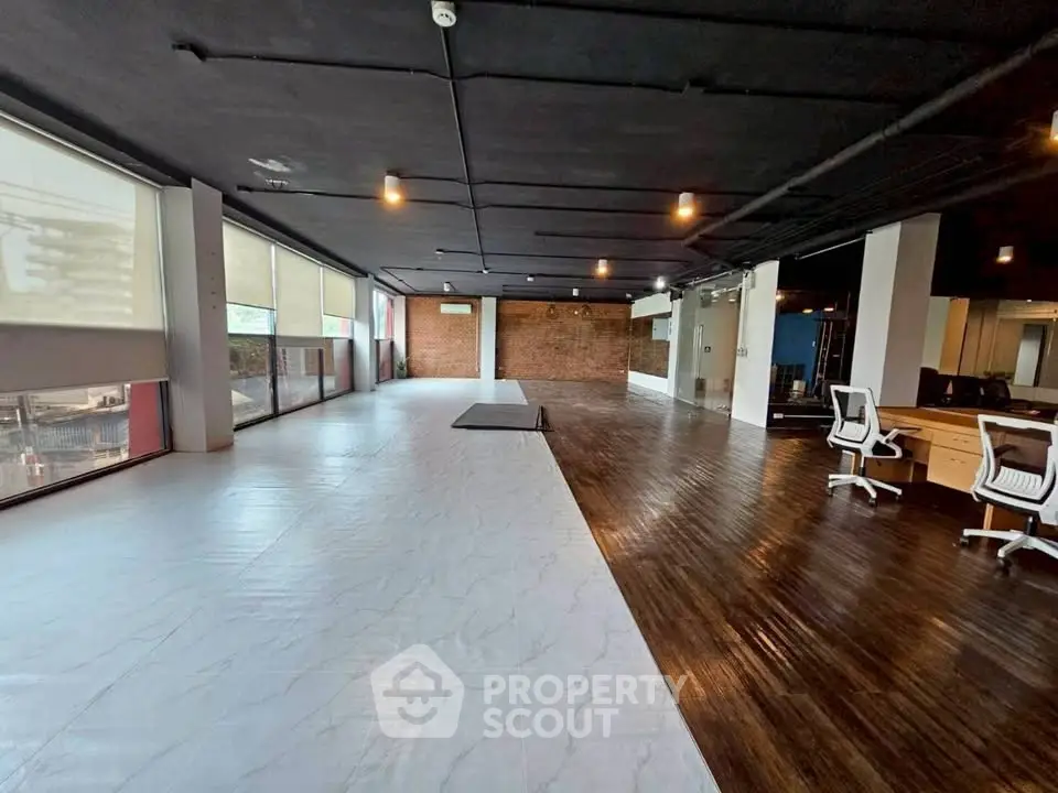 Spacious modern office space with wooden flooring and large windows for natural light.
