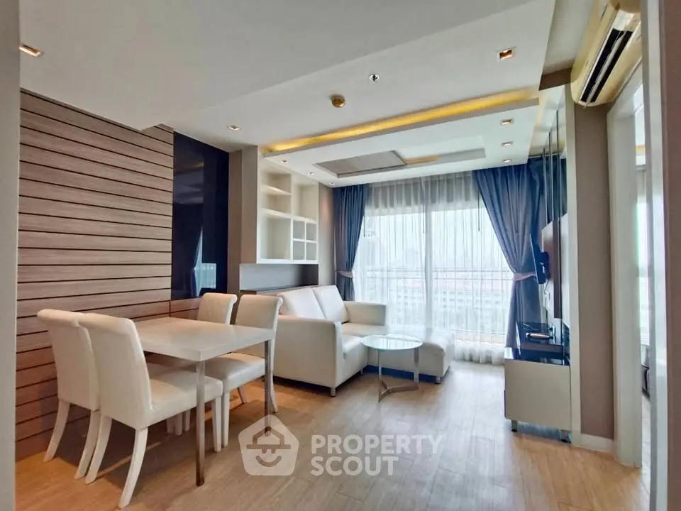 Modern living room with elegant dining area and large windows offering natural light.