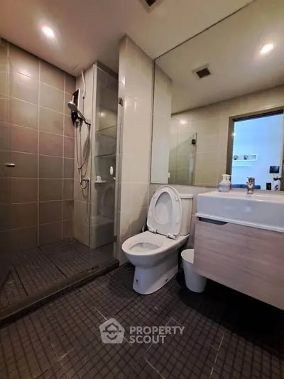 Modern bathroom with glass shower and sleek fixtures in contemporary apartment.