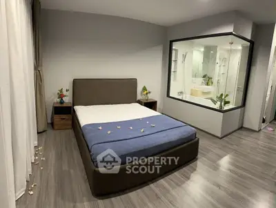 Modern bedroom with glass-walled ensuite bathroom and stylish decor