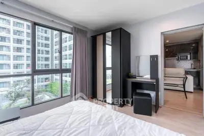 Modern bedroom with large windows and city view, featuring sleek furniture and neutral decor.