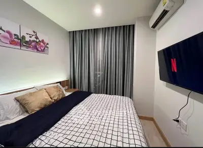 Modern bedroom with stylish decor and wall-mounted TV, featuring elegant curtains and cozy bedding.
