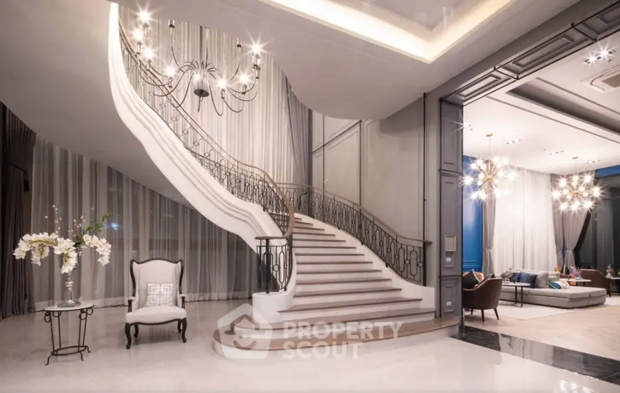 Luxurious living room with elegant staircase and modern chandelier lighting.
