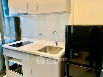 Modern kitchen with sleek appliances and compact design, featuring a built-in stove and spacious fridge.
