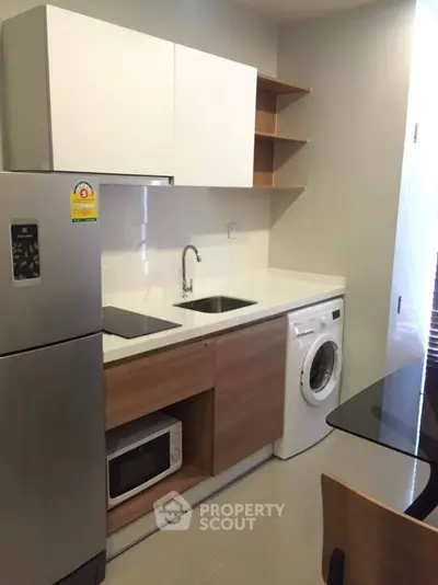 Modern kitchen with sleek appliances and integrated washing machine in compact layout.