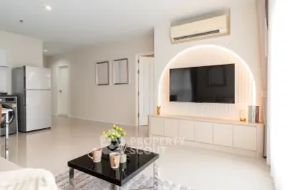 Modern living room with sleek design, featuring a mounted TV, air conditioning, and stylish decor.