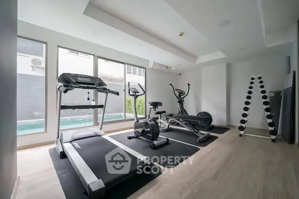 Modern home gym with exercise equipment and pool view