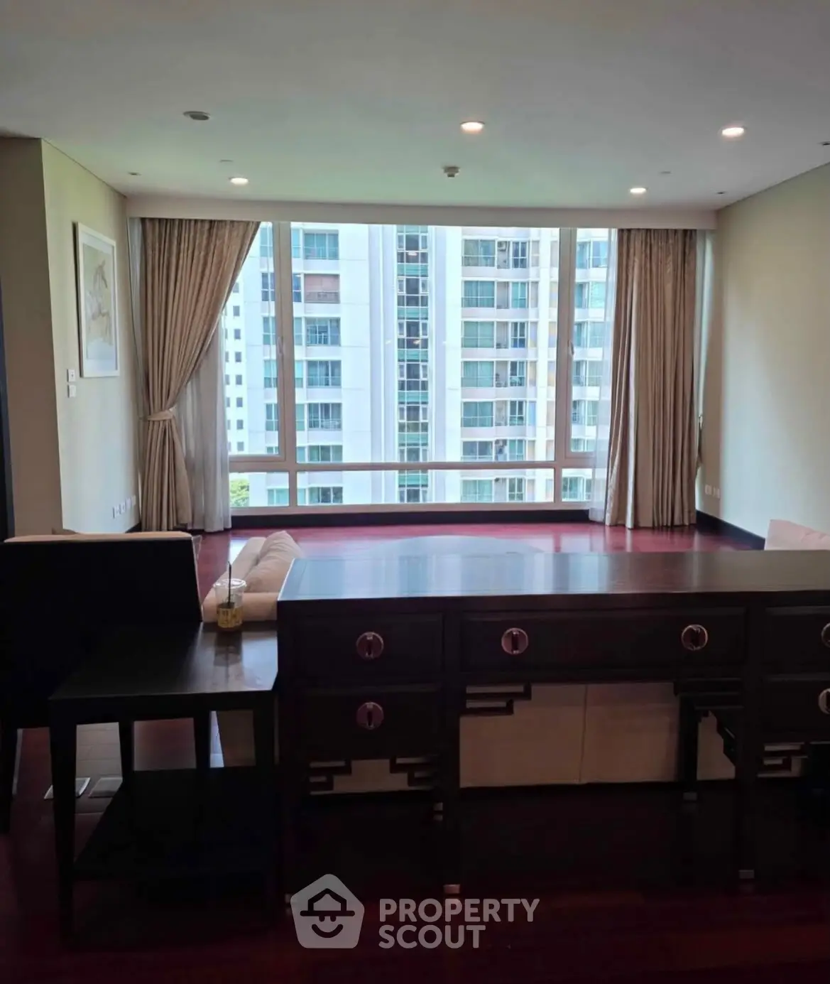 Spacious living room with large windows offering a stunning city view, elegant furniture, and natural light.