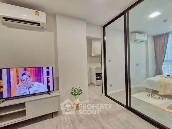 Modern apartment with open living room and bedroom, featuring sleek design and natural light.