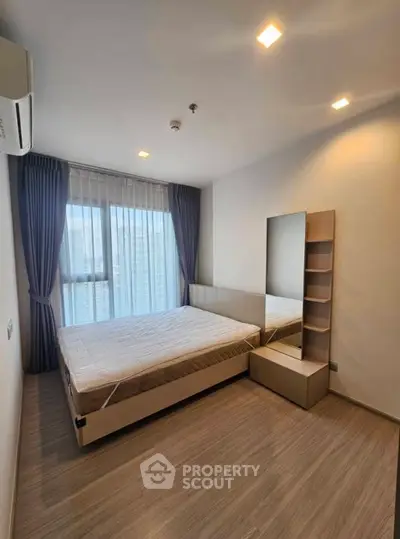Modern bedroom with large window and stylish decor in a high-rise apartment.
