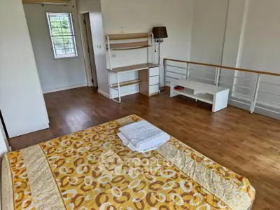 Spacious bedroom with wooden flooring and modern decor, featuring a cozy bed and ample natural light.
