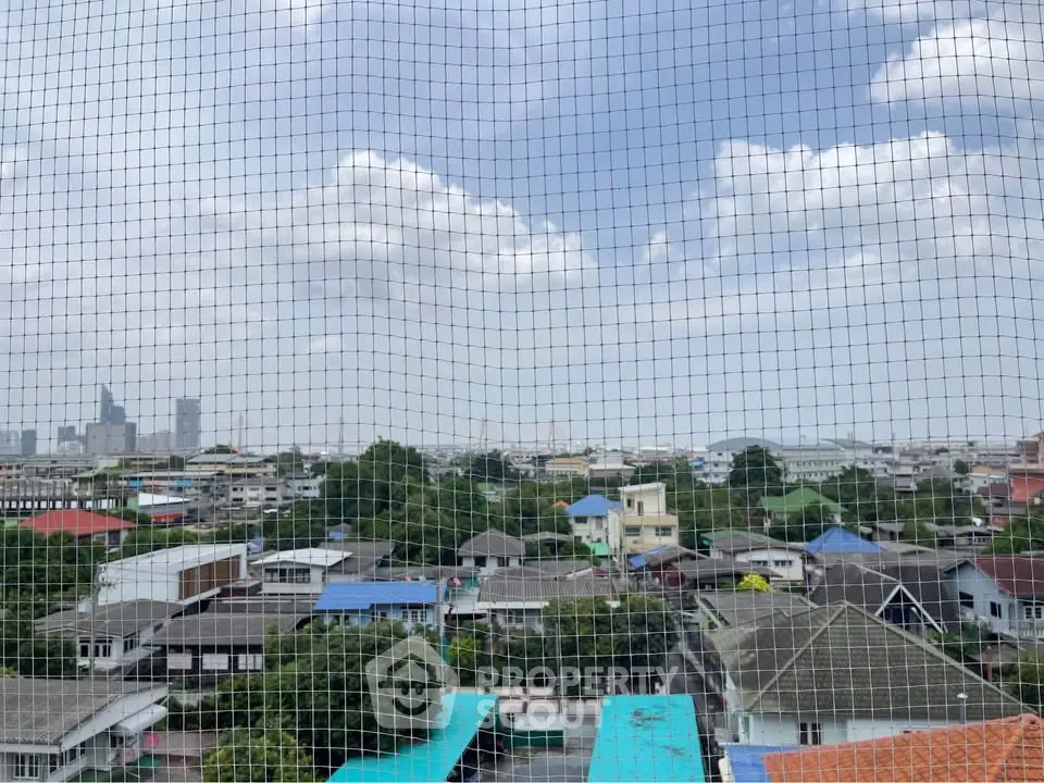 Stunning cityscape view from a high-rise balcony with protective netting.