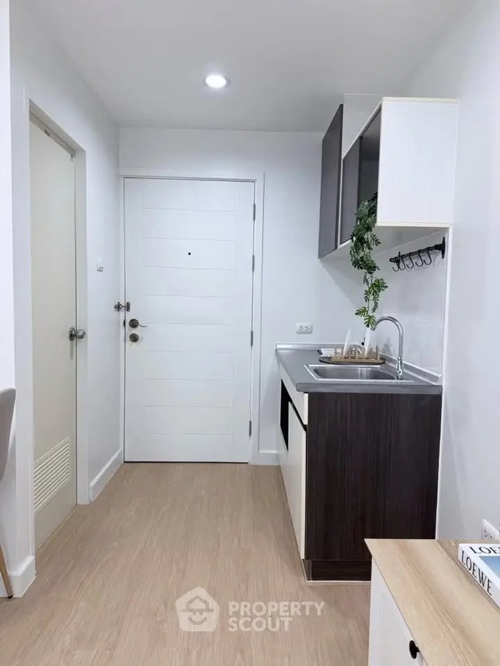 Modern compact kitchen with sleek cabinetry and wood flooring in a stylish apartment.