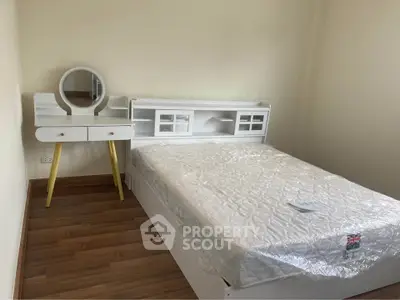 Cozy bedroom with modern white furniture and wooden flooring, perfect for a serene living space.