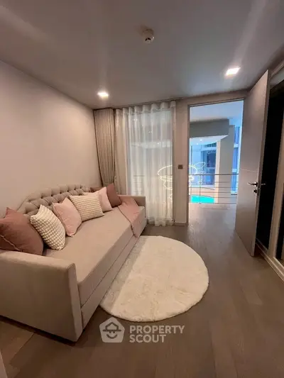 Cozy living room with plush sofa and modern decor, overlooking a pool view.