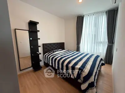 Cozy bedroom with modern decor and ample natural light, featuring a stylish bed and floor-to-ceiling curtains.