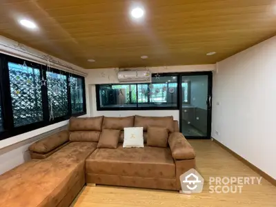 Spacious living room with cozy brown sectional sofa and large windows for natural light.