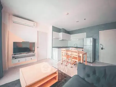 Modern open-layout living room with kitchen, featuring sleek furniture and appliances.