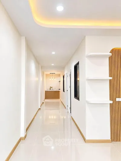 Sleek modern hallway with recessed lighting leading to a stylish kitchen area.