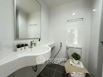 Modern bathroom with sleek fixtures and minimalist design, featuring a large mirror and stylish decor.
