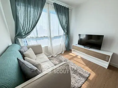 Cozy living room with modern sofa, TV, and large windows with elegant curtains.