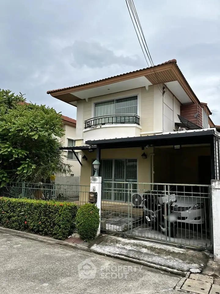 Charming two-story house with lush greenery and secure parking in a serene neighborhood.