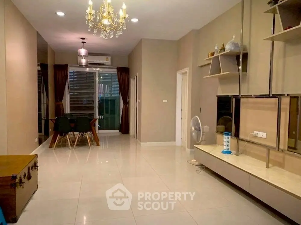 Spacious living room with elegant chandelier and modern dining area in a stylish apartment.