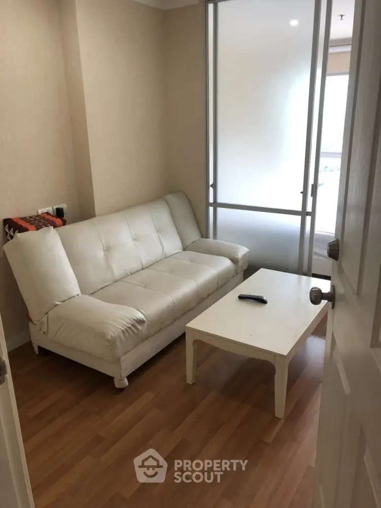 Cozy living room with white sofa and wooden flooring, perfect for relaxation.