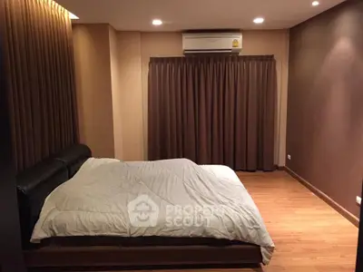 Cozy bedroom with wooden flooring and modern lighting, featuring a comfortable bed and air conditioning.