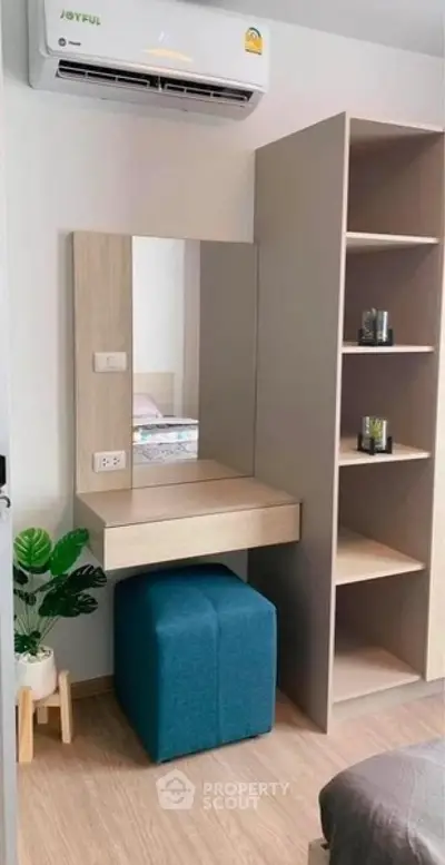 Modern bedroom with stylish vanity and shelving, featuring air conditioning and cozy decor.