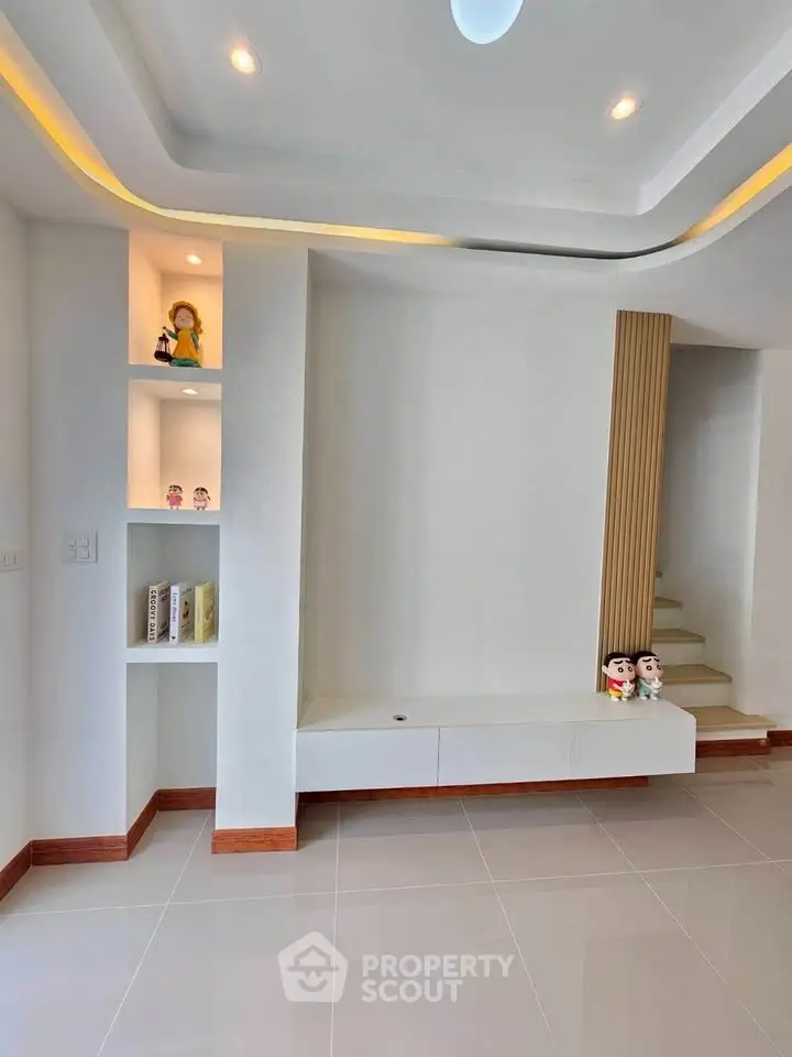 Modern minimalist living room with built-in shelves and staircase