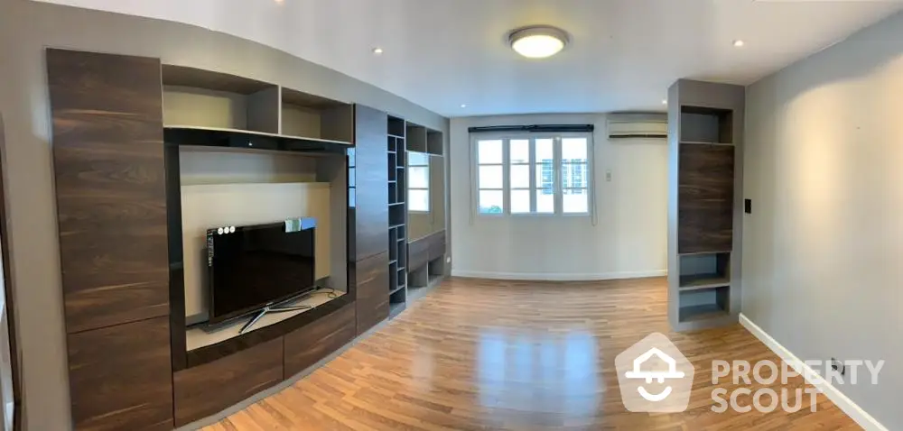 Spacious living room with modern built-in entertainment center and hardwood floors