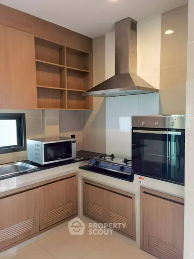 Modern kitchen with gas stove, oven, and microwave in sleek wooden cabinetry.