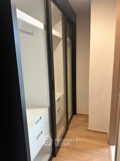 Spacious walk-in closet with sliding glass doors and wooden flooring
