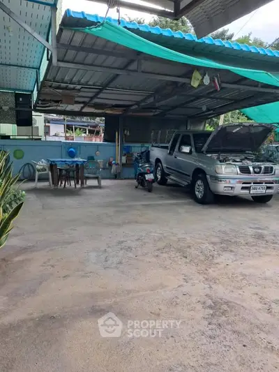 Spacious covered parking area with vehicle and outdoor seating in residential property.