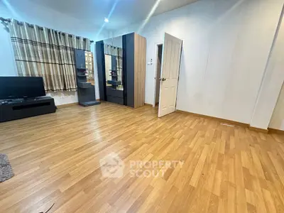 Spacious living room with wooden flooring and modern furniture, perfect for relaxation and entertainment.