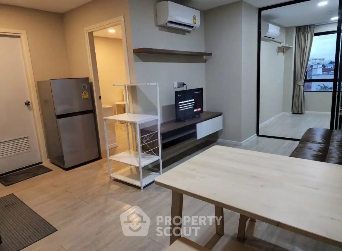 Modern apartment interior with open living area and kitchen, featuring sleek furniture and air conditioning.