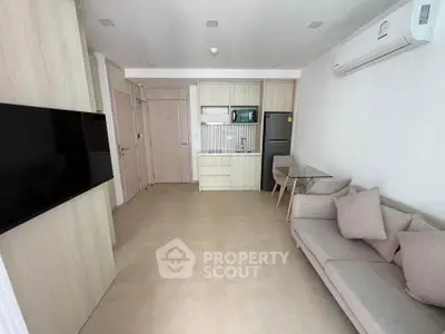 Modern open-plan living room with sleek kitchen and cozy seating area in a stylish apartment.