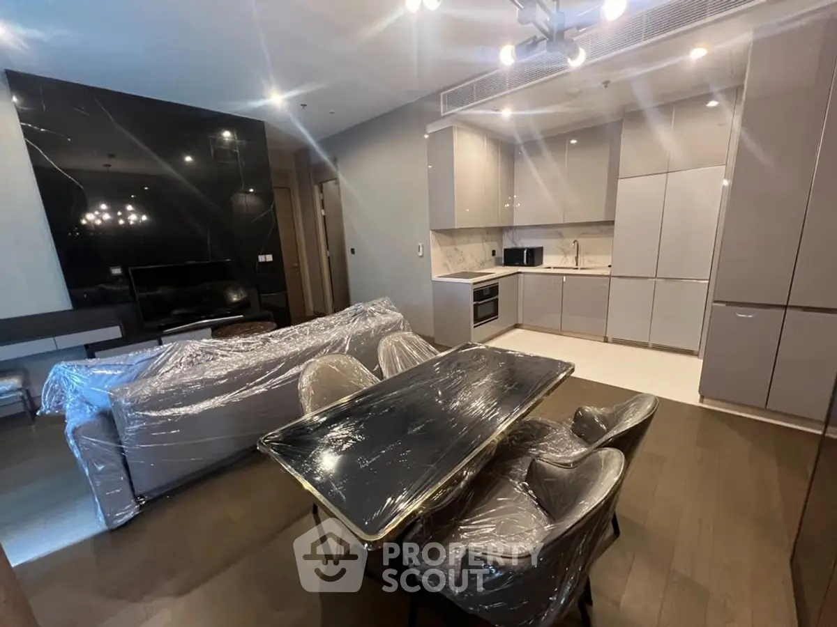 Modern open-layout living room and kitchen with sleek furniture and appliances, perfect for contemporary living.