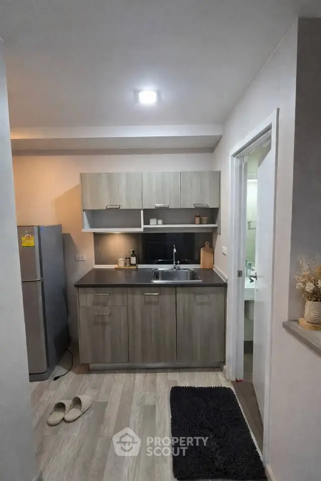 Modern compact kitchen with sleek cabinetry and stainless steel appliances in cozy apartment.