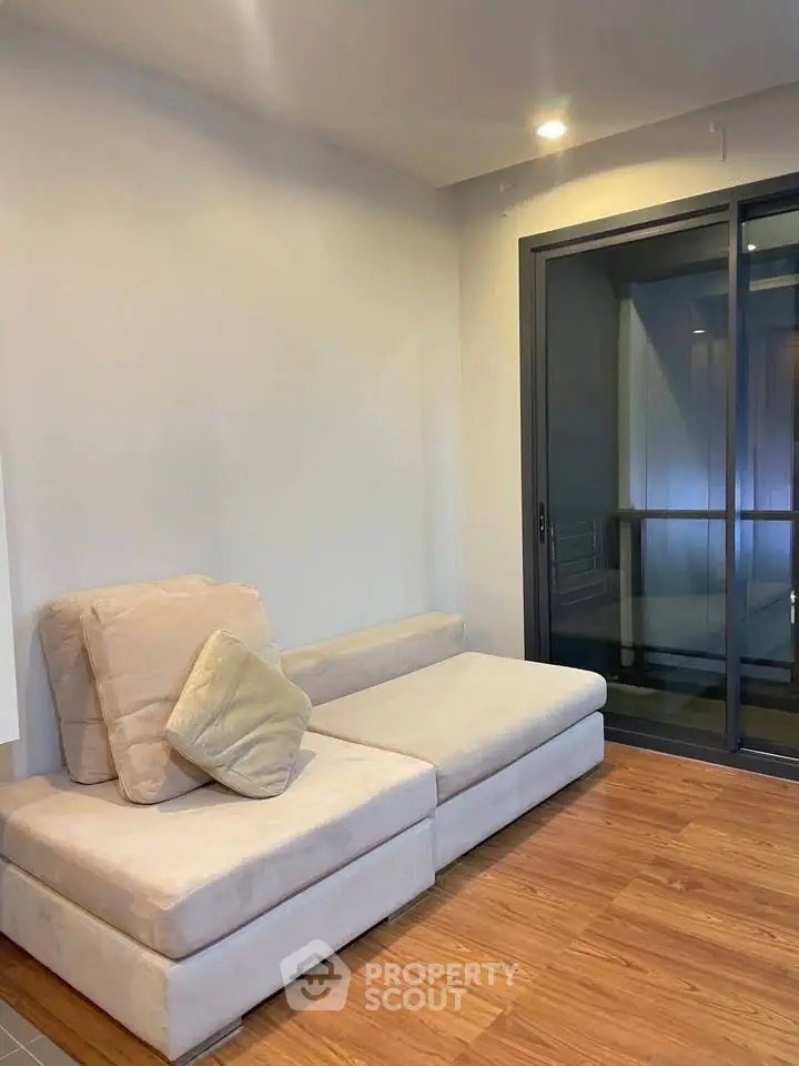 Modern living room with cozy beige sofa and sliding glass doors leading to balcony.