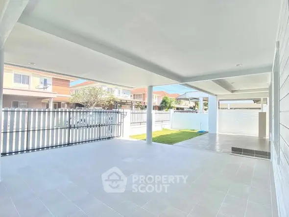 Spacious covered patio with tiled flooring and garden view in suburban home.