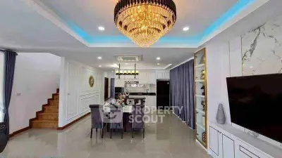 Luxurious open-plan living room with elegant chandelier and modern kitchen.