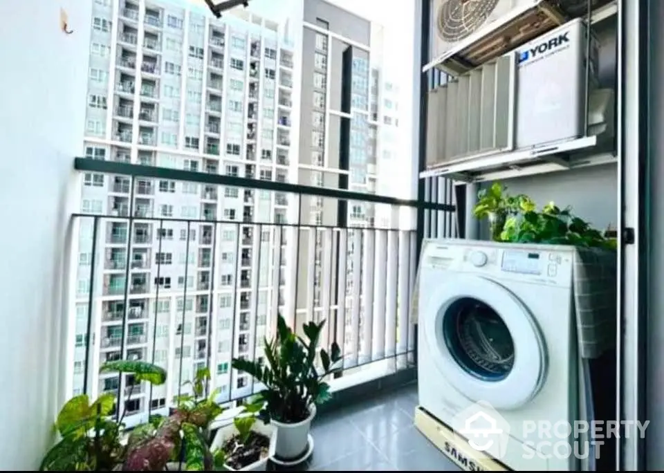 Modern balcony with washing machine and plants overlooking cityscape.