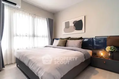 Modern bedroom with stylish decor and natural light, featuring a cozy bed and elegant artwork.