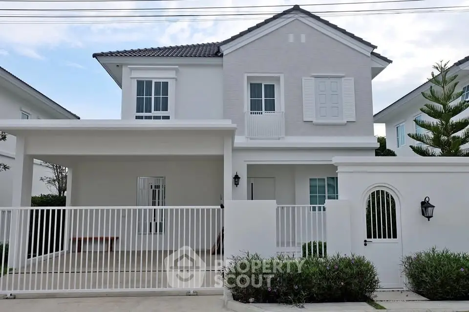 Charming two-story house with modern facade and gated driveway in serene neighborhood.