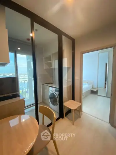 Modern apartment interior with kitchen, dining area, and view of bedroom and balcony.