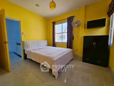 Bright bedroom with yellow walls and natural light, featuring a cozy bed and modern furnishings.