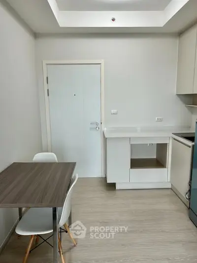 Modern minimalist kitchen with sleek white cabinetry and compact dining area.