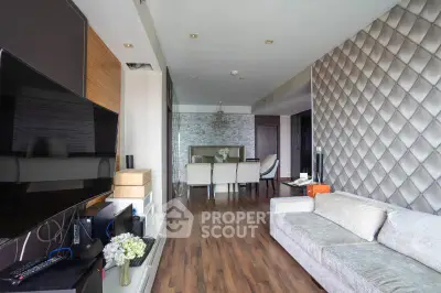 Modern living room with elegant decor and hardwood flooring, featuring a large TV and comfortable seating area.
